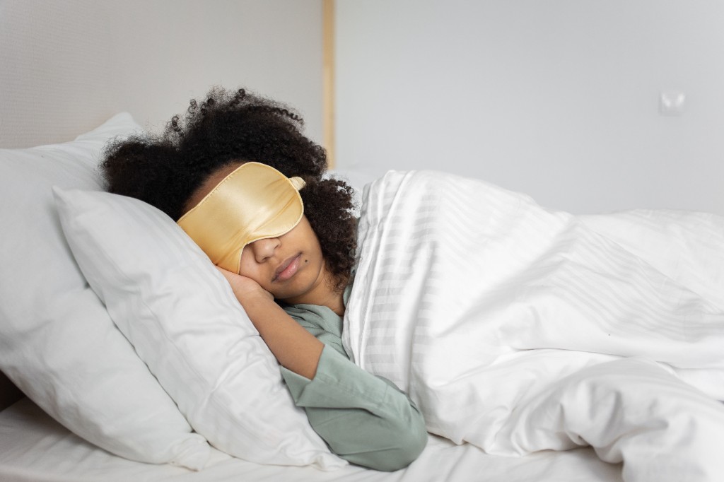 Woman resting in bed wearing a sleep mask