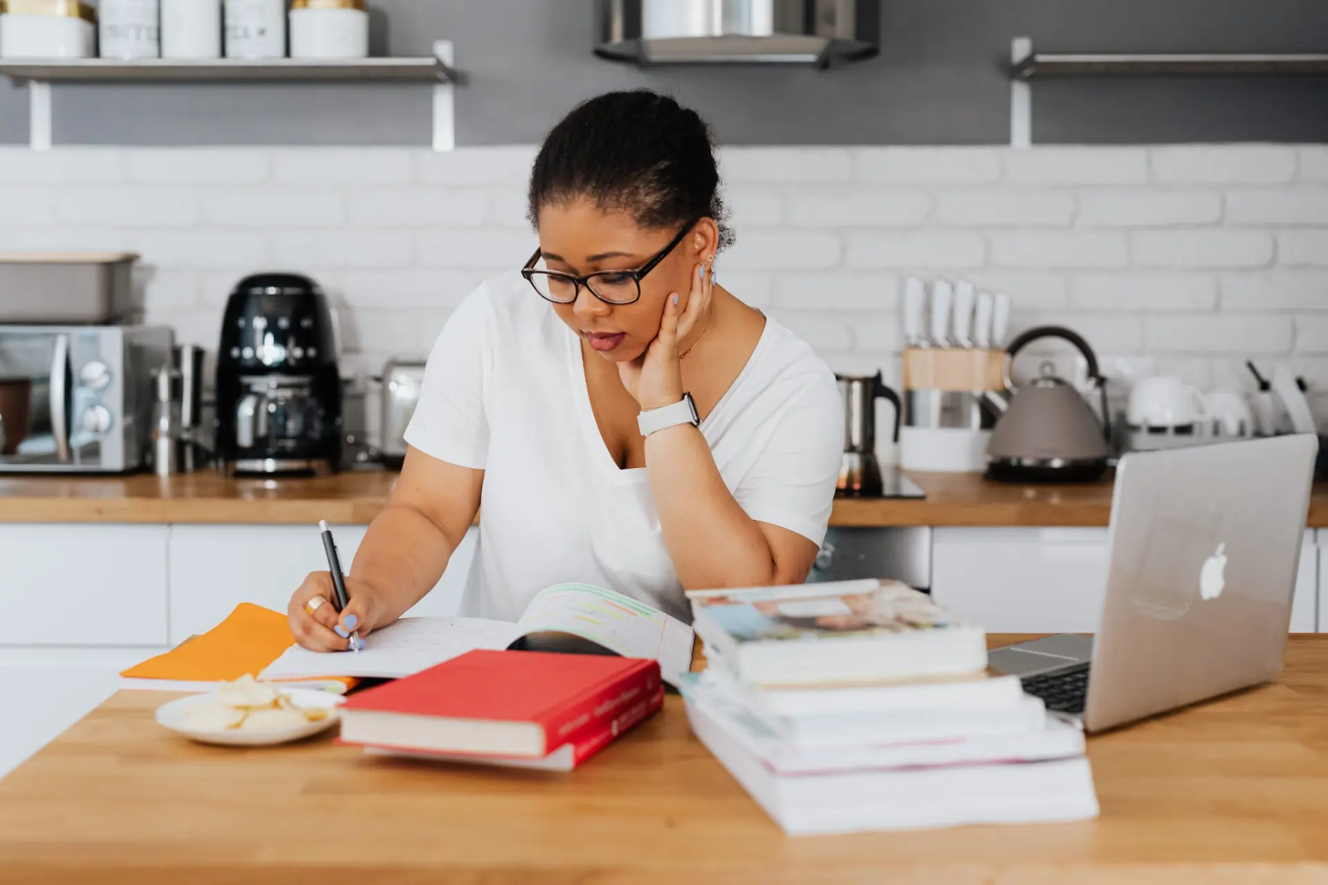 Woman writing in a notebook at a kitchen table